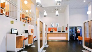 A modern reception area with a counter, seating, and vending machines. - ibis budget Wien Messe (Vienna)