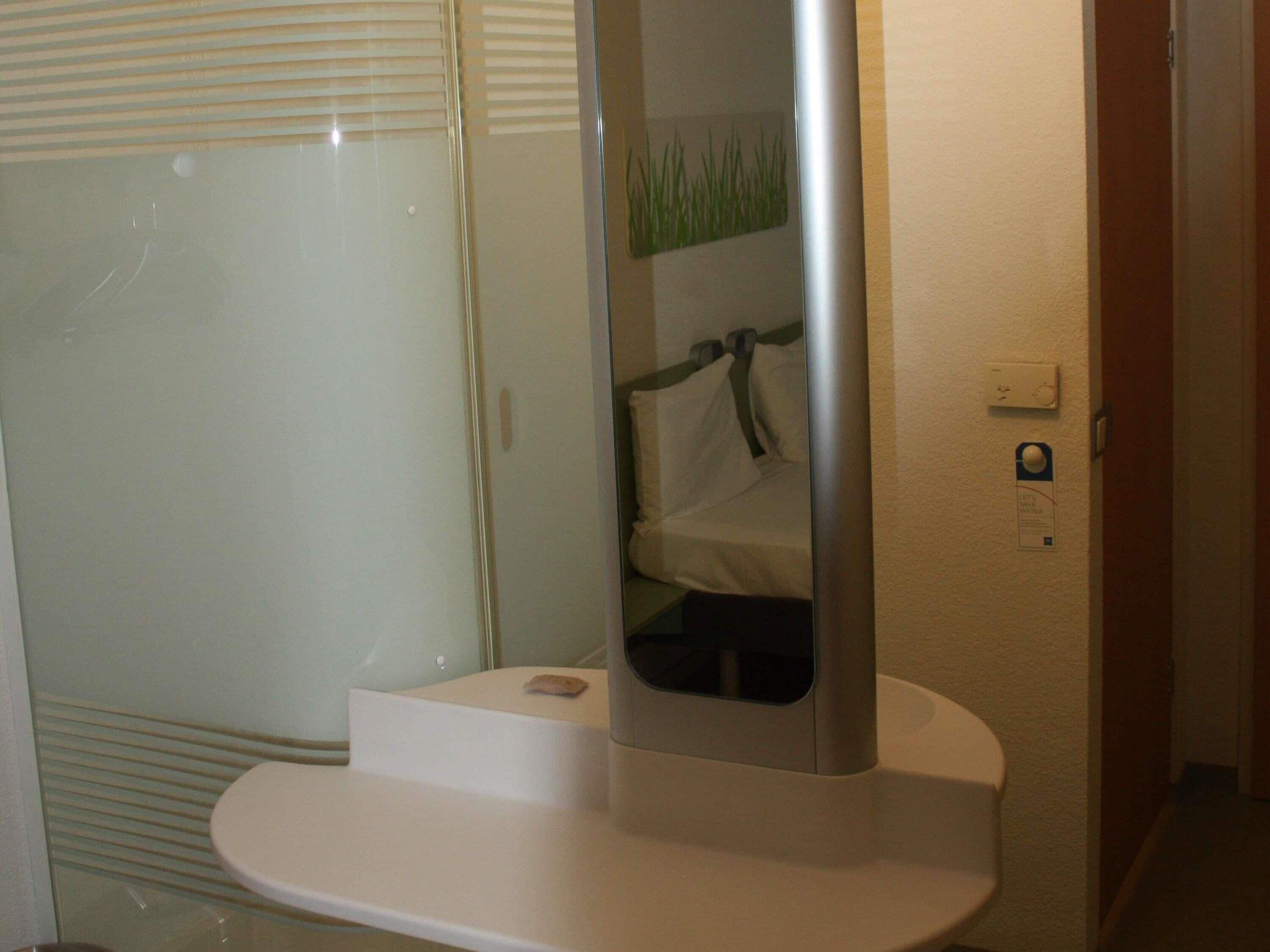 A bathroom with a white sink, a mirror, and a towel rack.