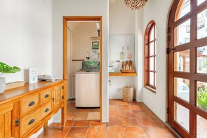 A narrow hallway with a wooden cabinet, a small refrigerator, and a window with a view of the outside.