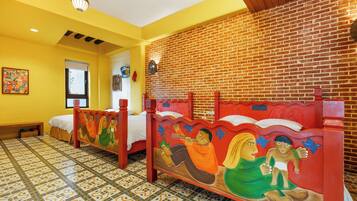 Una habitación con dos camas, cada una con un cabecero pintado diferente, suelo de baldosas y pared de ladrillo.