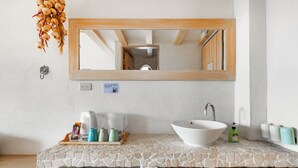 A bathroom with a stone countertop, a white sink, a mirror, and a wooden cabinet. - Kenting Fairyland & Farm Guest House (Hengchun)