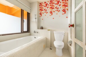 A bathroom with a bathtub, toilet, and a window with a view of the outside.