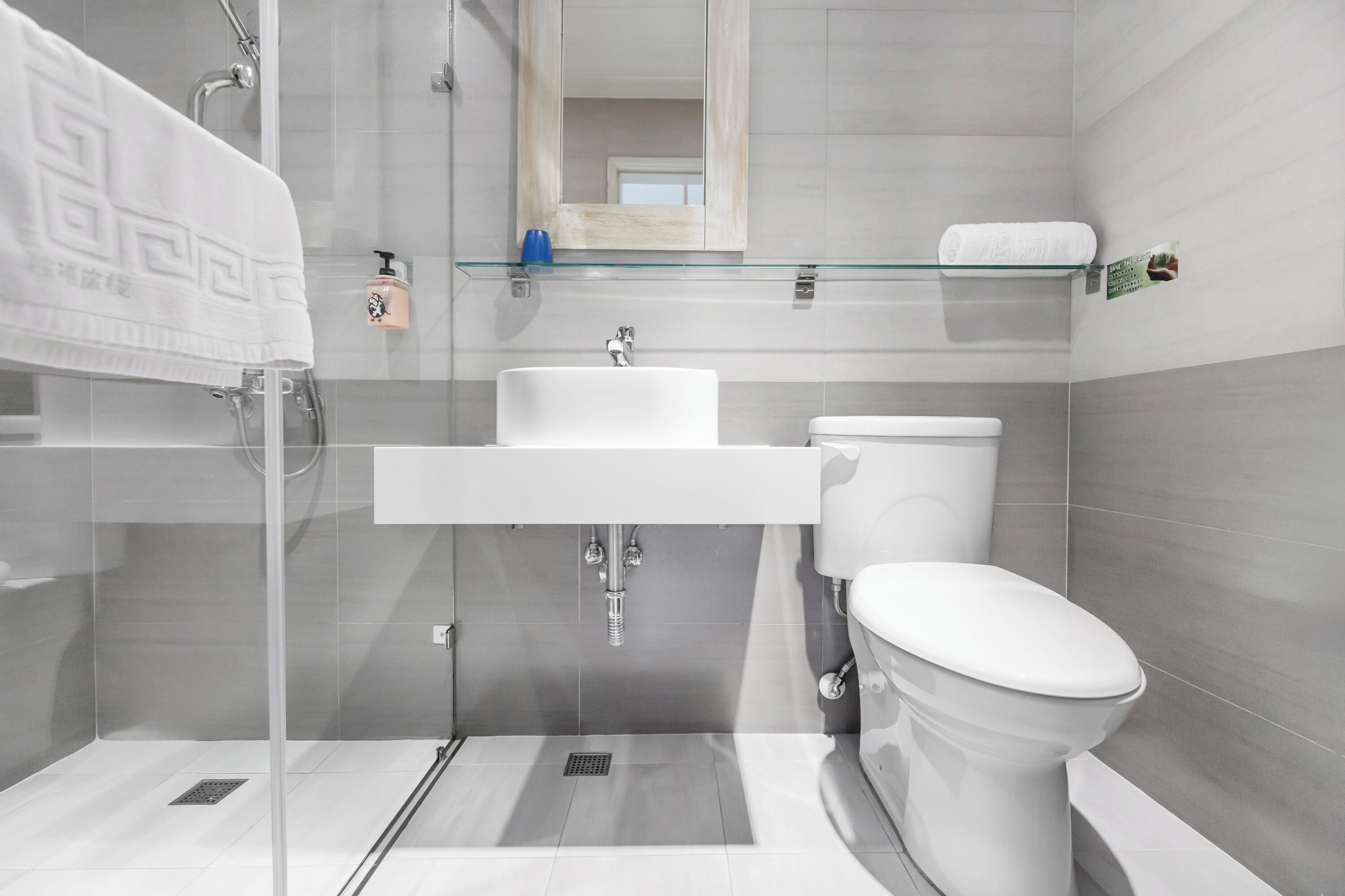 Ein modernes Badezimmer mit Duschkabine aus Glas, einem weißen Waschbecken und einer Toilette.