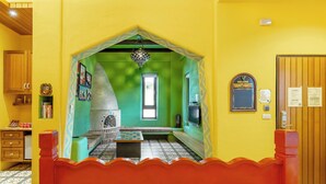 A room with a bed, a small table, a green wall, a wooden door, and a window. - Kenting Fairyland & Farm Guest House (Hengchun)