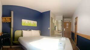 A hotel room with a large bed, a desk, a chair, and a bathroom visible through an open door. - ibis budget Belfast City Centre (Belfast)