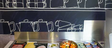 Un bufé con diversas opciones de comida, incluyendo carnes, quesos y frutas.
