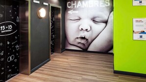 Un moderno vestíbulo de hotel con piso de madera, un elevador empotrado en la pared y un gran anuncio publicitario en la pared.