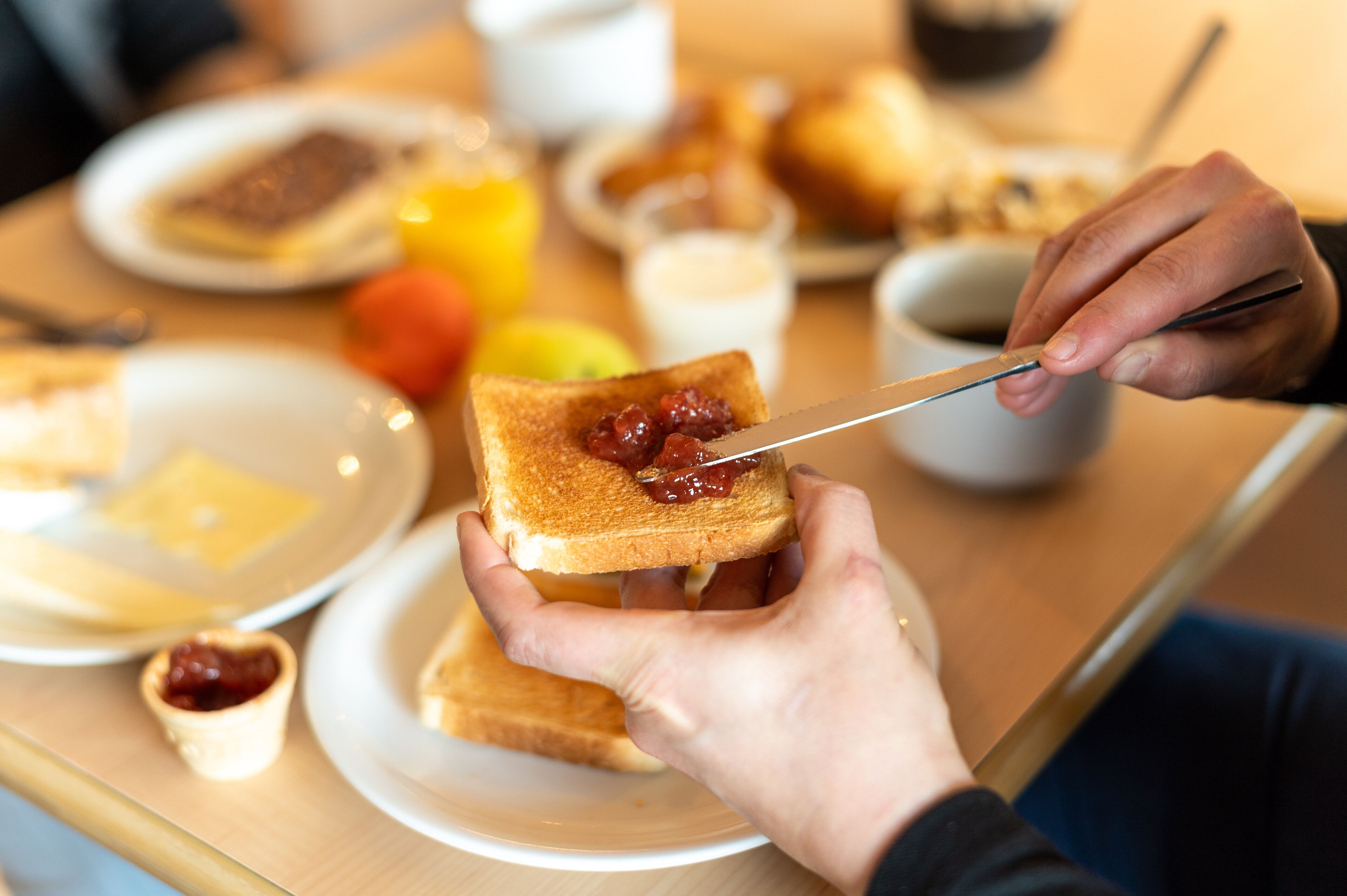 Une table mise pour le petit-déjeuner avec des tartines, de la confiture et un couteau.