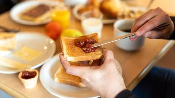 Une table mise pour le petit-déjeuner avec des tartines, de la confiture et un couteau.