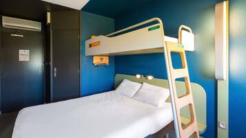 A bunk bed in a room with a blue wall, a door with a sign, and a small shelf.