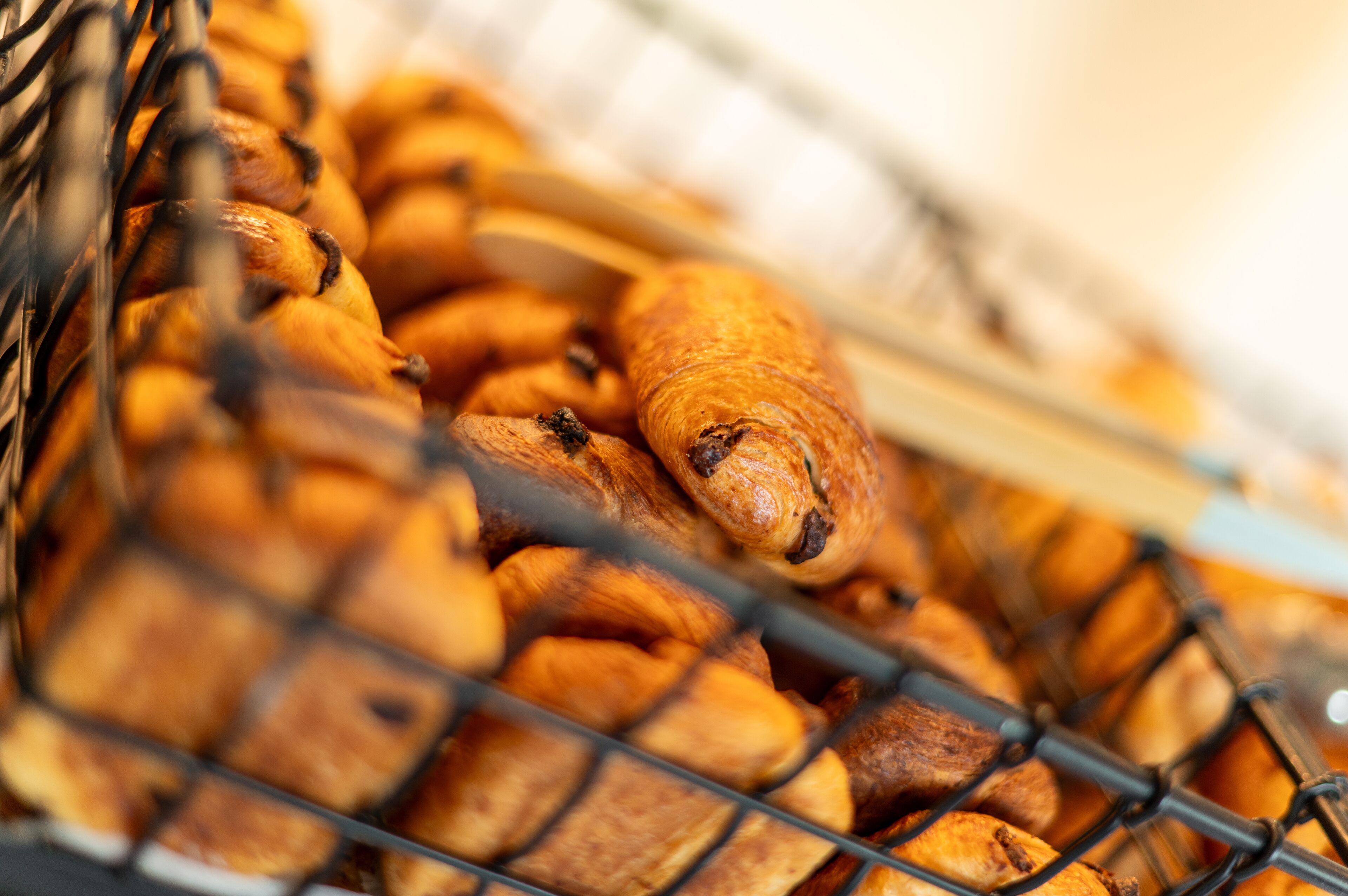 A basket of assorted baked goods, including croissants and other pastries, displayed in a wire basket.