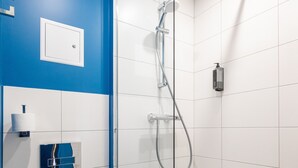 Un baño moderno con cabina de ducha de vidrio, azulejos blancos, una pared de acento azul y un inodoro.