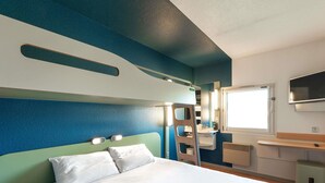 Habitación de hotel con cama, baño con lavamanos y espejo, y televisor montado en la pared.