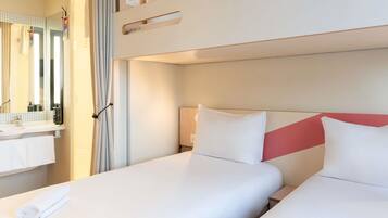 Habitación de hotel con literas, baño con espejo y ventana.