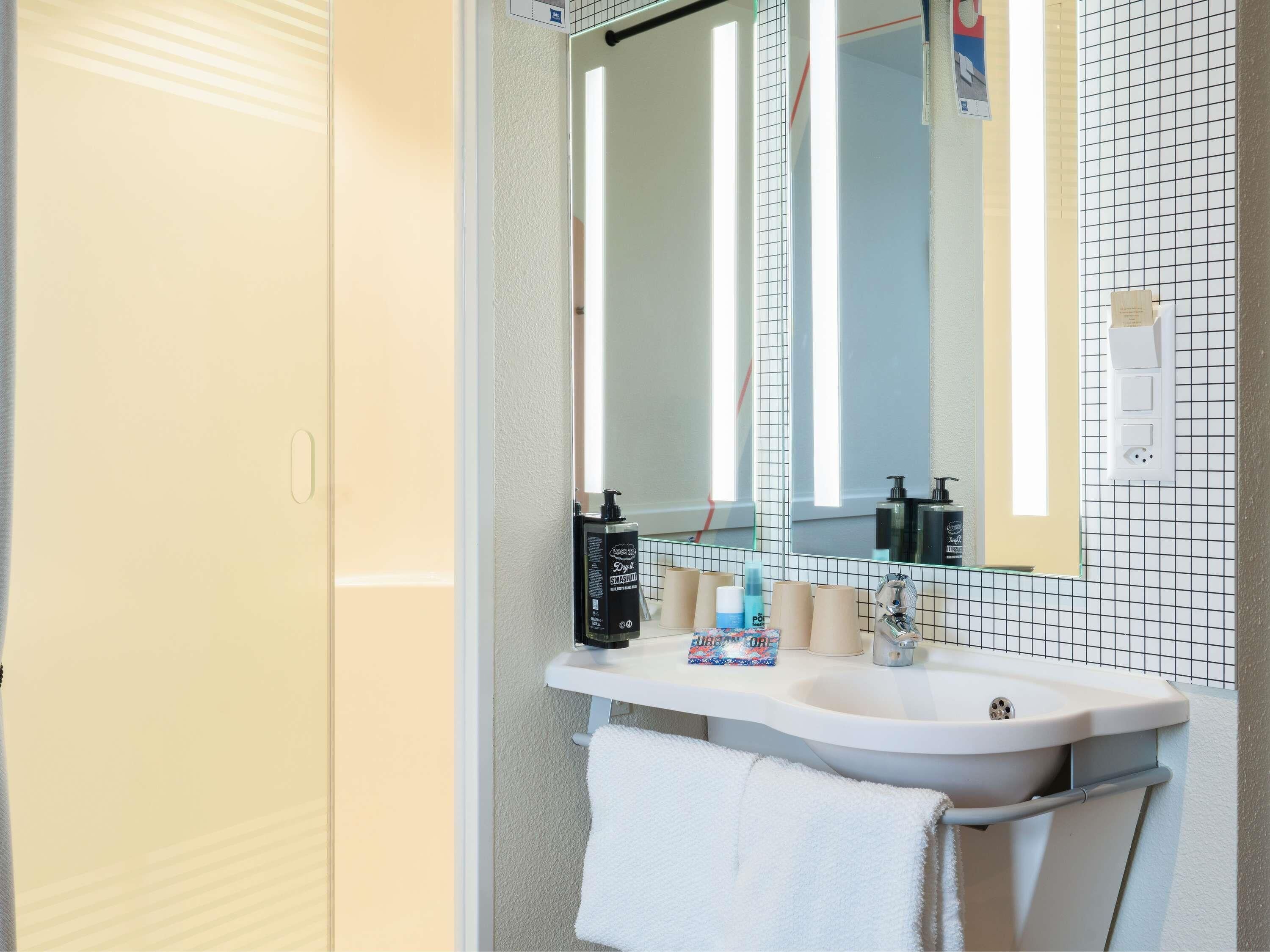 Une salle de bain avec un lavabo blanc, un miroir et un porte-serviettes.