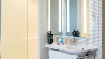 Une salle de bain avec un lavabo blanc, un miroir et un porte-serviettes.