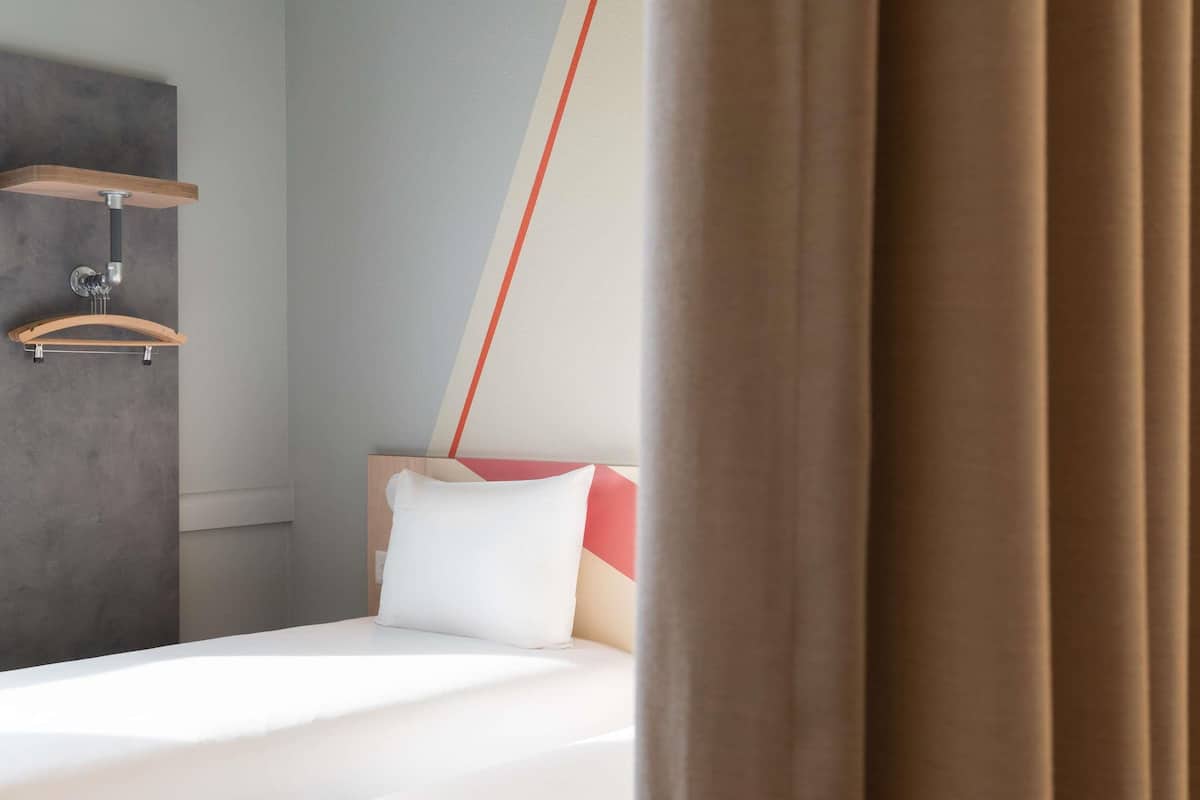 Ein Hotelzimmer mit Bett, einer Holzablage und einem Wandtuchhalter.
