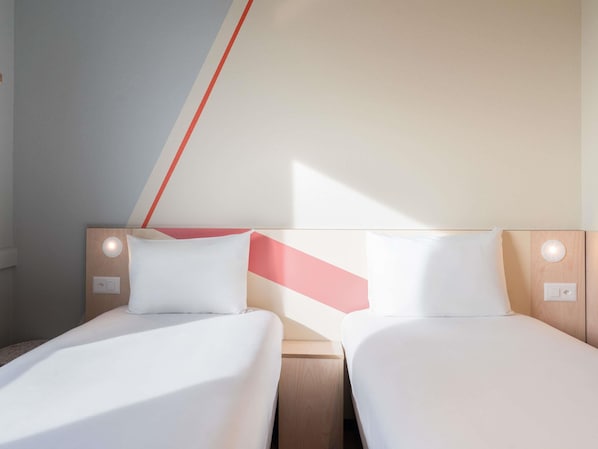 Dos camas individuales con cabeceros de madera, ropa de cama blanca y lámparas de noche.