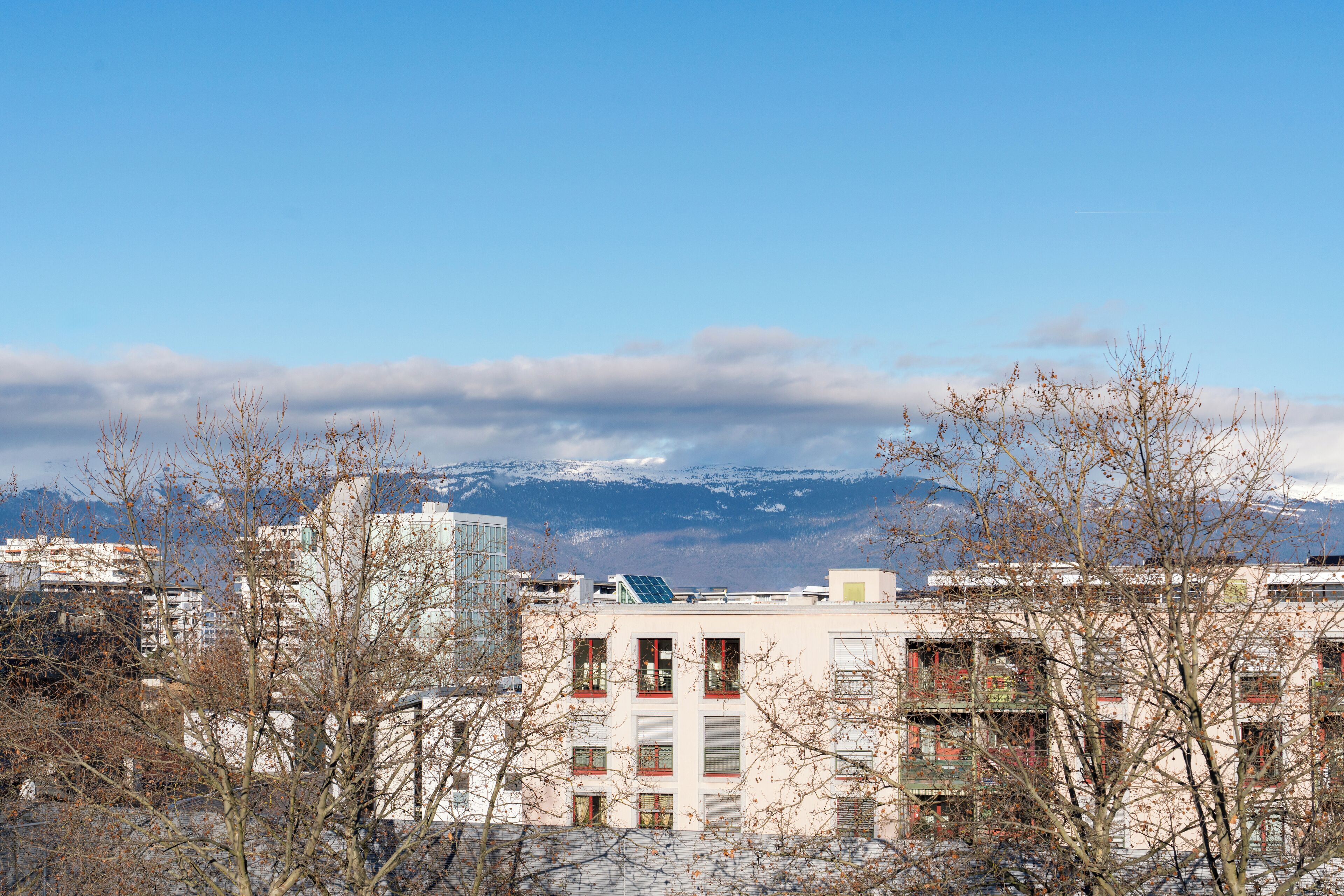 A cityscape with buildings, a clear sky, and mountains in the background.