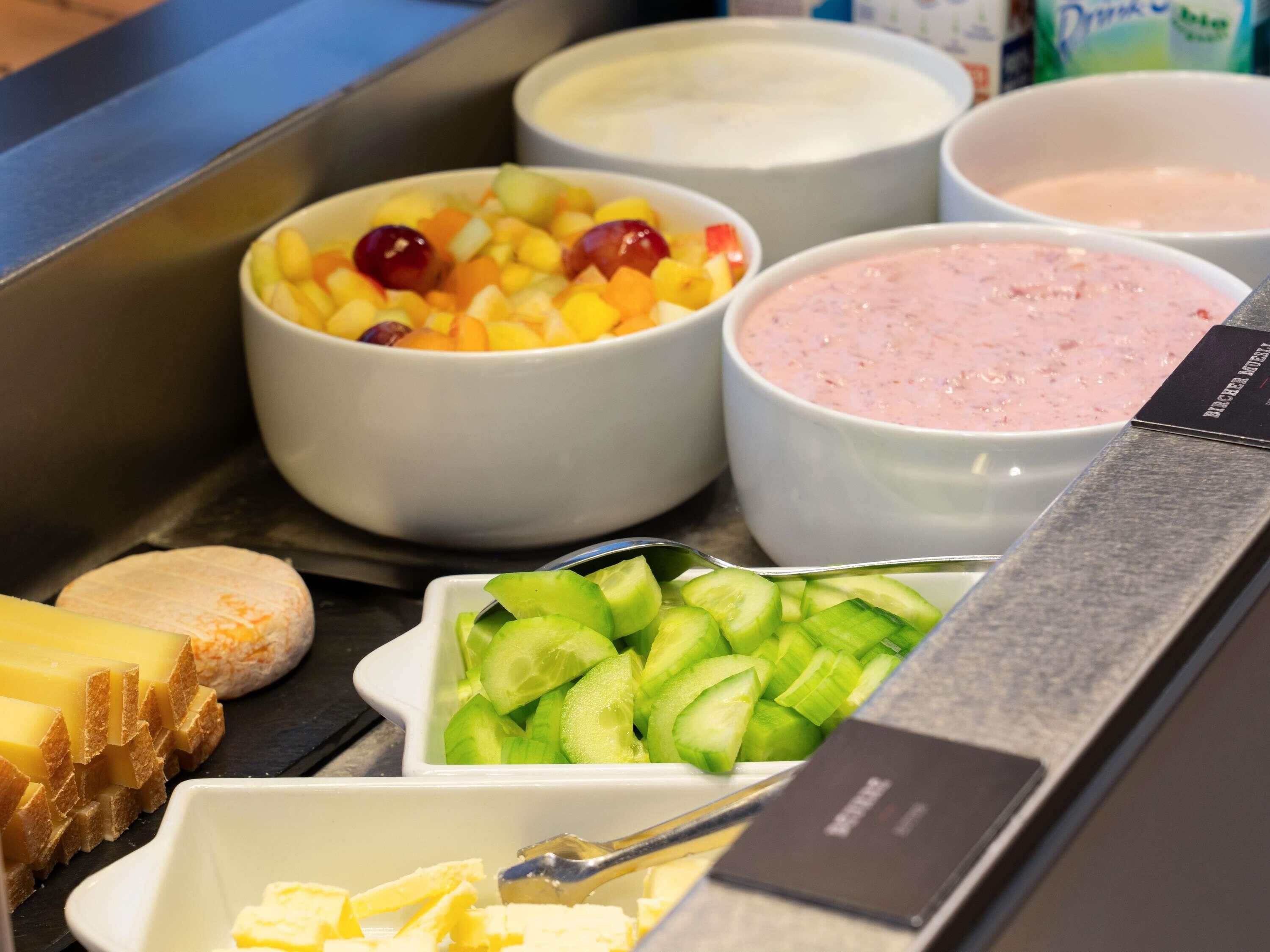 Buffet com diversos alimentos, incluindo frutas, queijos e patês.