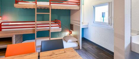 A bunk bed room with a window, a table, and a chair.