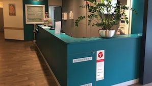 A reception desk with a plant, a sign indicating pickup services, and a counter with a computer.