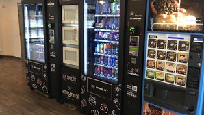 A row of vending machines with various food and drink options, including coffee and snacks.