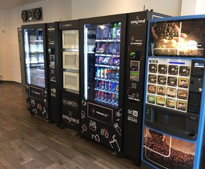 Une rangée de distributeurs automatiques proposant une variété d’aliments et de boissons, notamment du café et des en-cas.