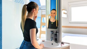 A bathroom with a sink, mirror, and window.