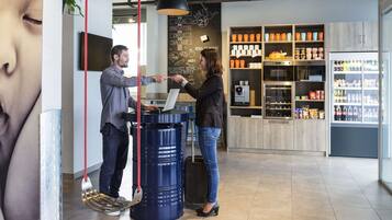 L’intérieur d’un café moderne est doté d’un écran numérique affichant le menu, d’une machine à café et d’un réfrigérateur rempli de boissons.