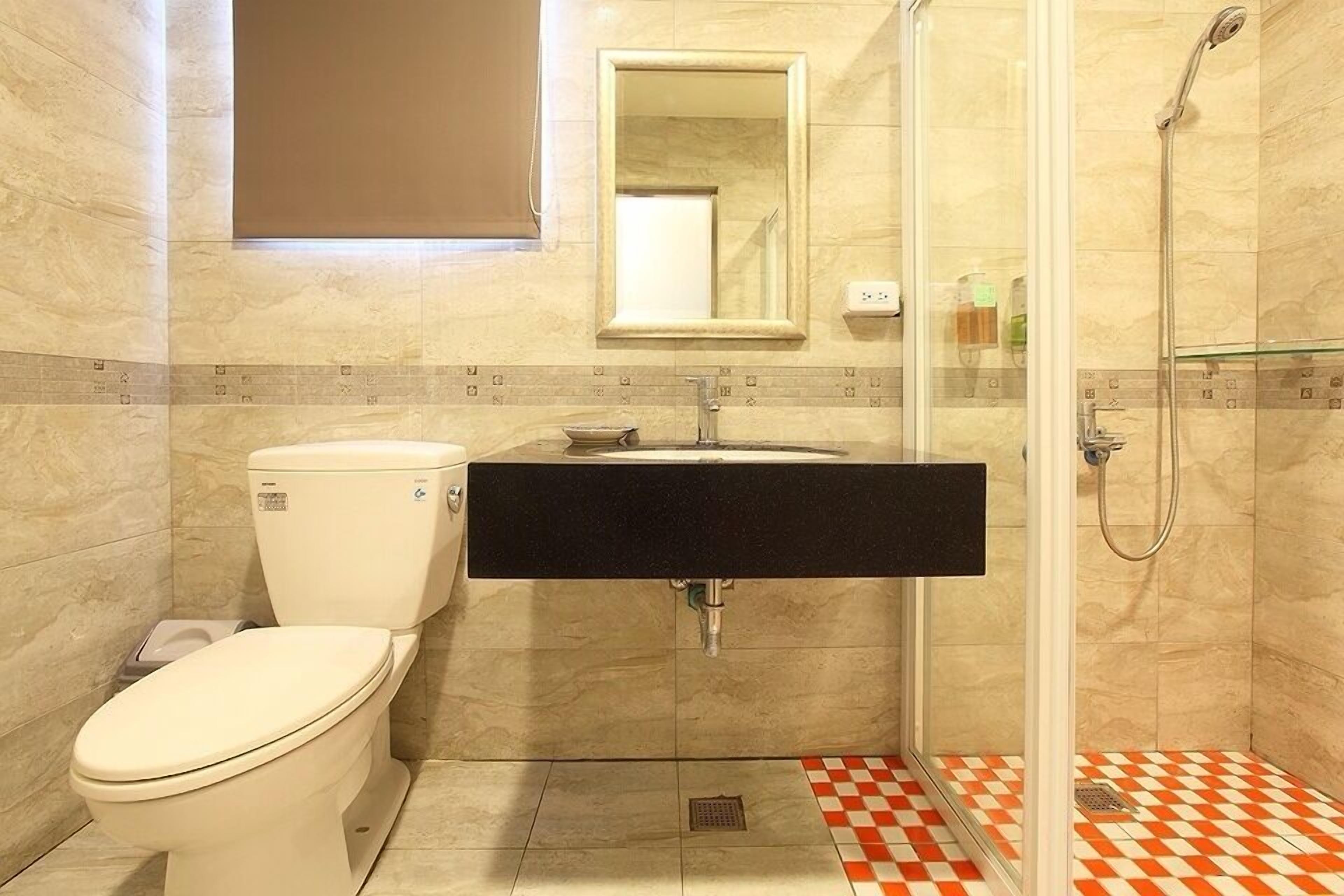 A bathroom with a toilet, sink, and shower.