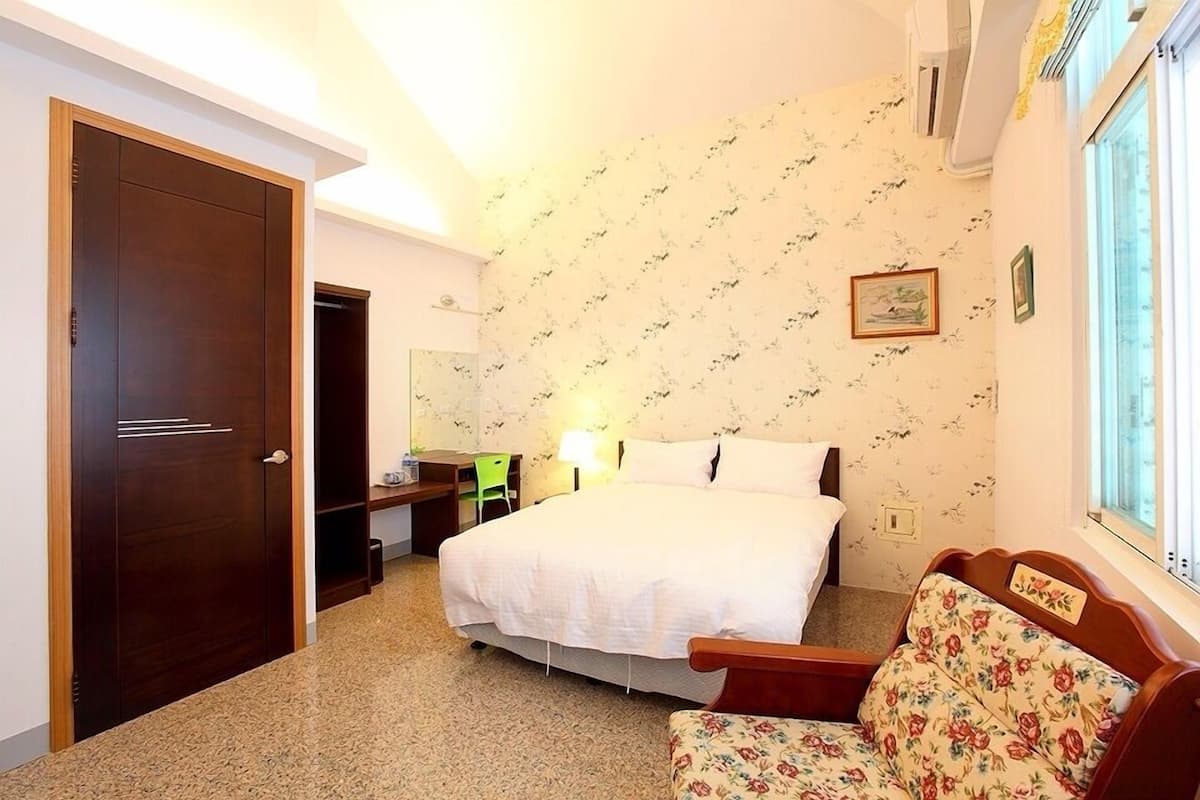 Una habitación de hotel con cama, escritorio, silla y sofá.