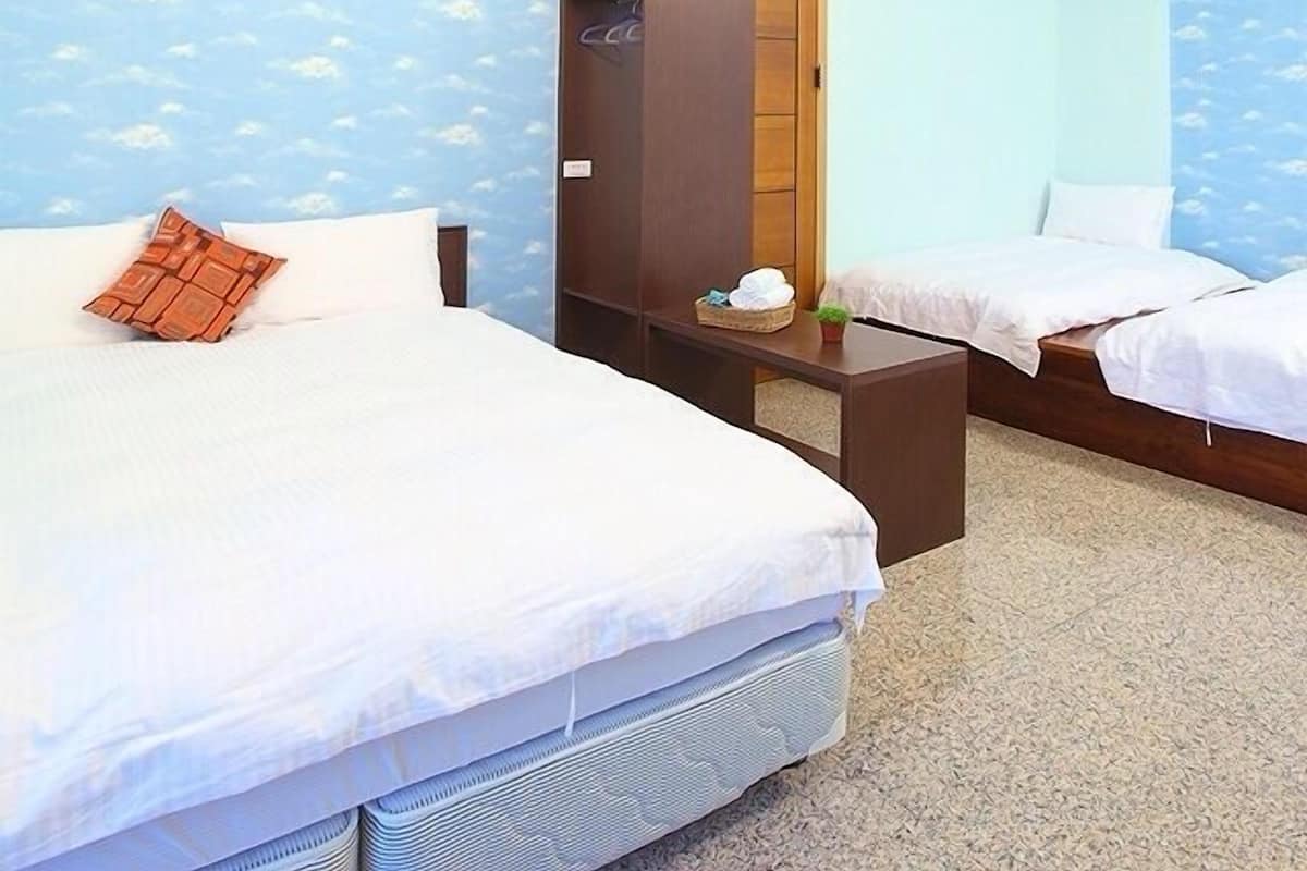 Una habitación de hotel con dos camas, un armario y una pared con diseño de nubes.