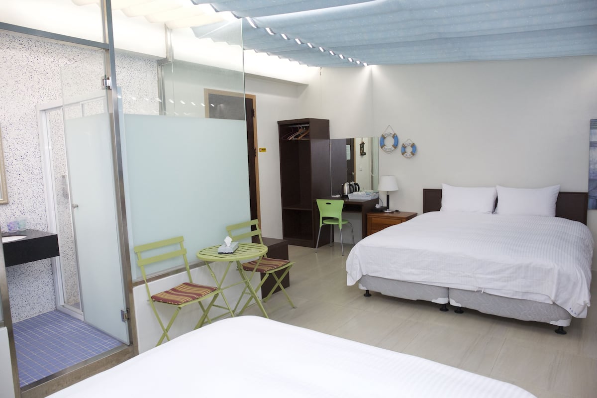 Una habitación de hotel con cama, escritorio, silla, armario y zona de ducha.
