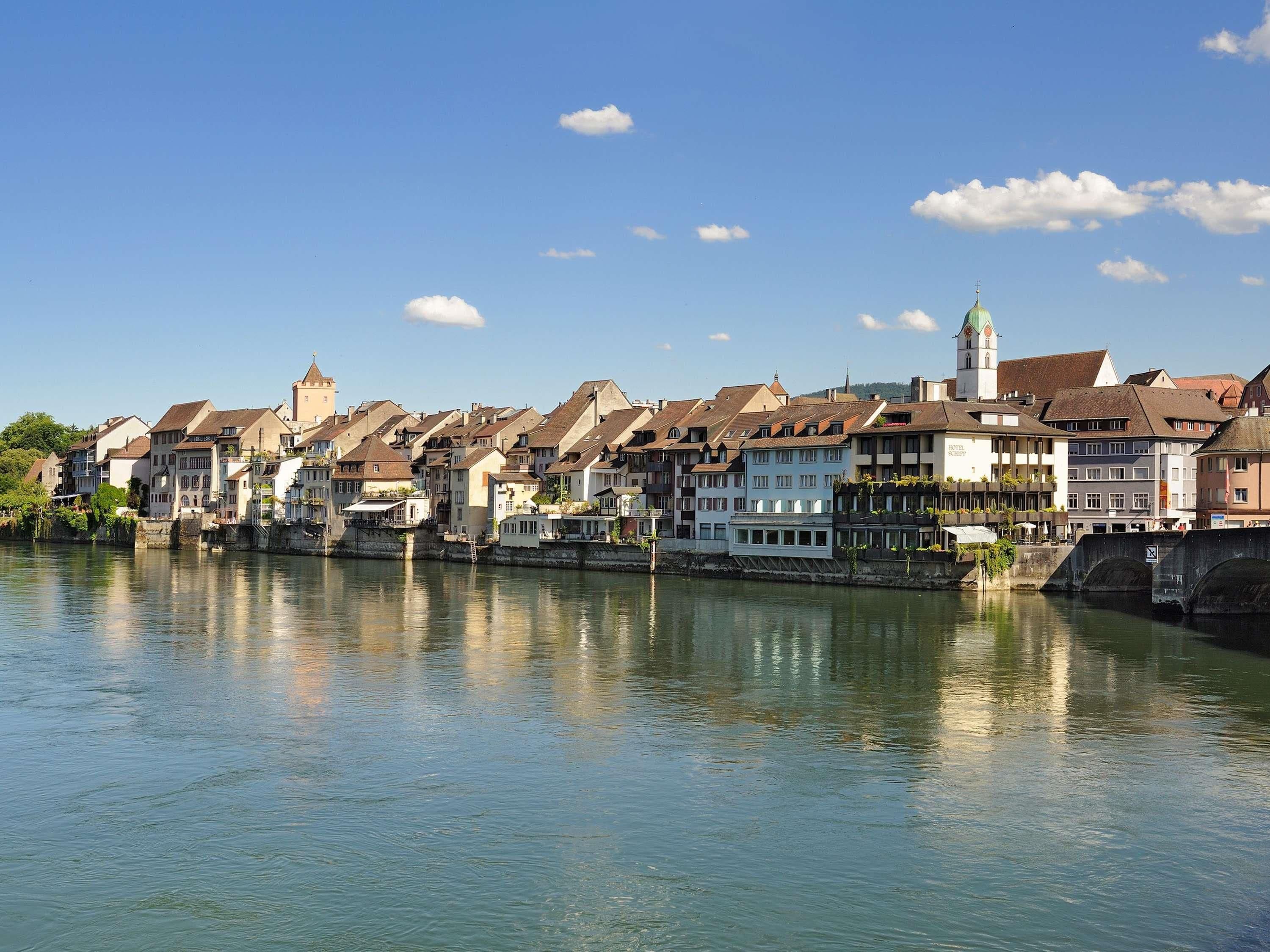 Een stad aan de rivier met historische gebouwen, een opvallende toren en een brug.