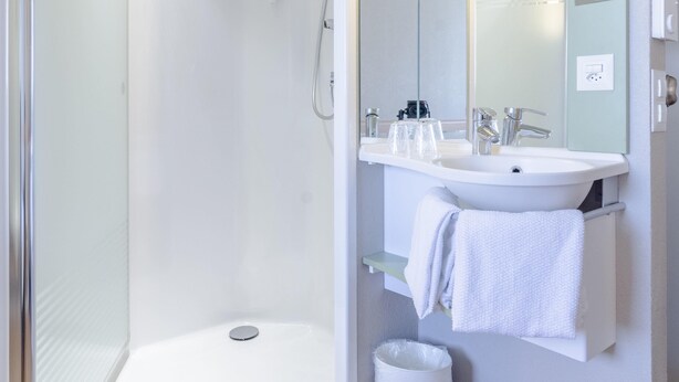 A modern bathroom with a shower, sink, and toilet. - ibis budget Basel City (Basel)