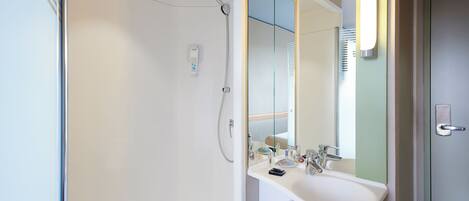 A modern bathroom with a glass shower enclosure, a white sink, and a mirror with a light above it.
