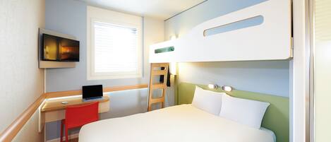 Habitación de hotel con literas, un escritorio con una computadora portátil, un televisor y una ventana con persianas.