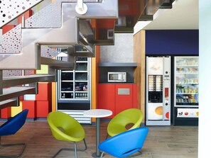 Un intérieur moderne comprenant un distributeur automatique, un espace salon et un four à micro-ondes.