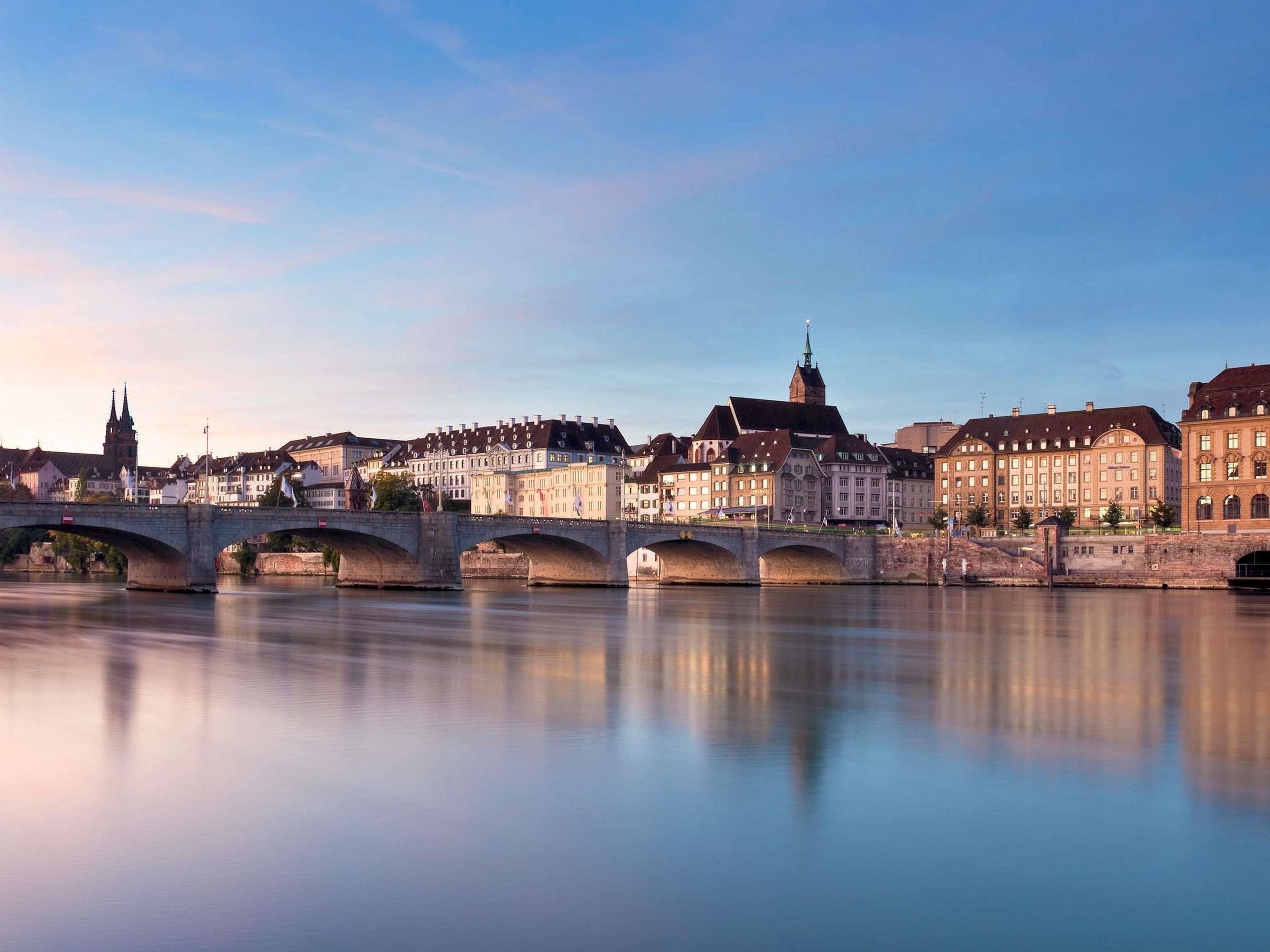A historic bridge over a calm river with buildings on either side, including a prominent church spire.