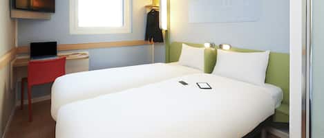 A hotel room with a bed, a desk, a chair, a TV, and a window.