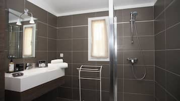 Un baño moderno con un espejo grande, un lavamanos blanco, cabina de ducha con mampara de cristal y un perchero para toallas.