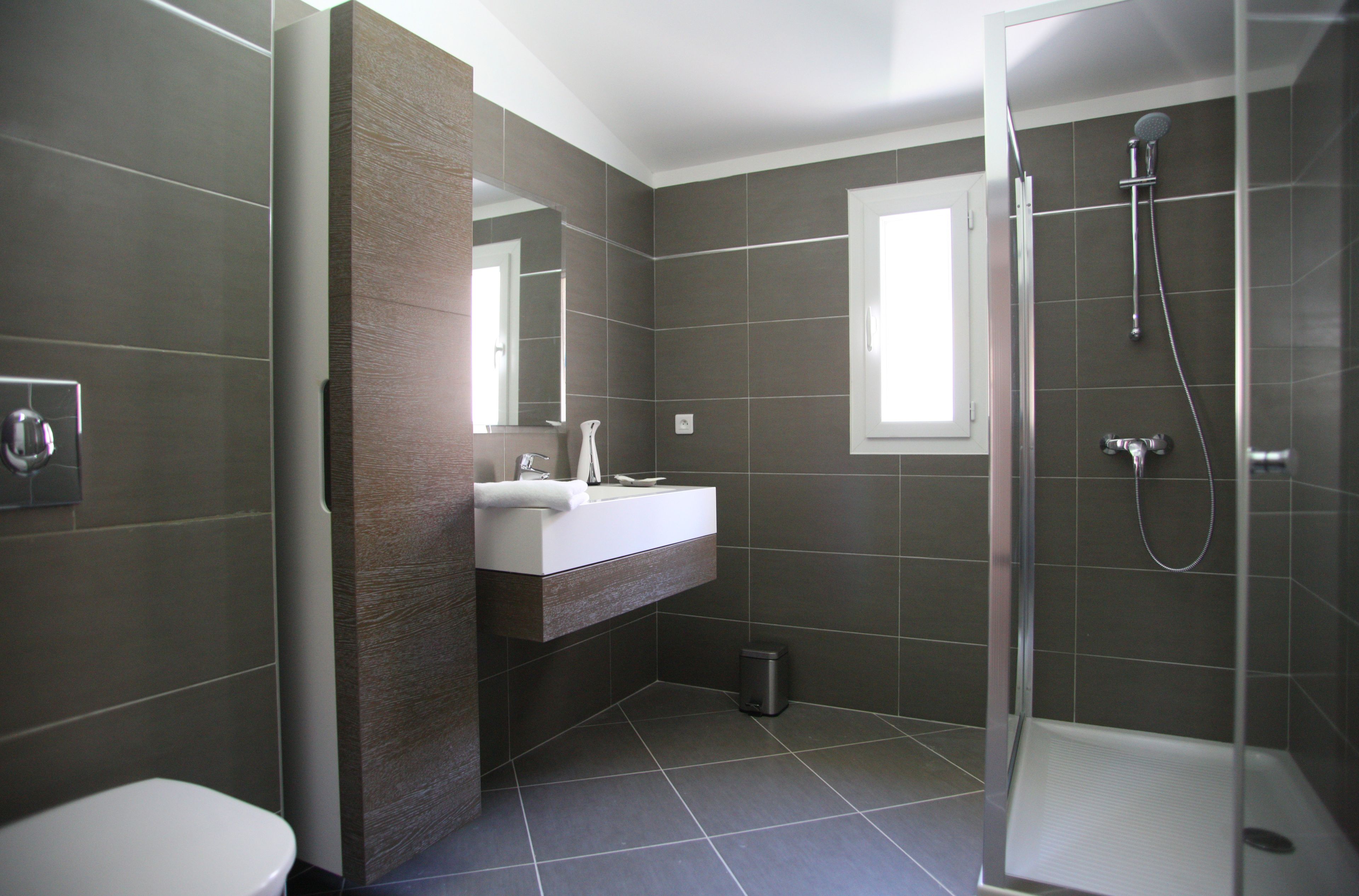 A modern bathroom with a shower, toilet, and vanity.