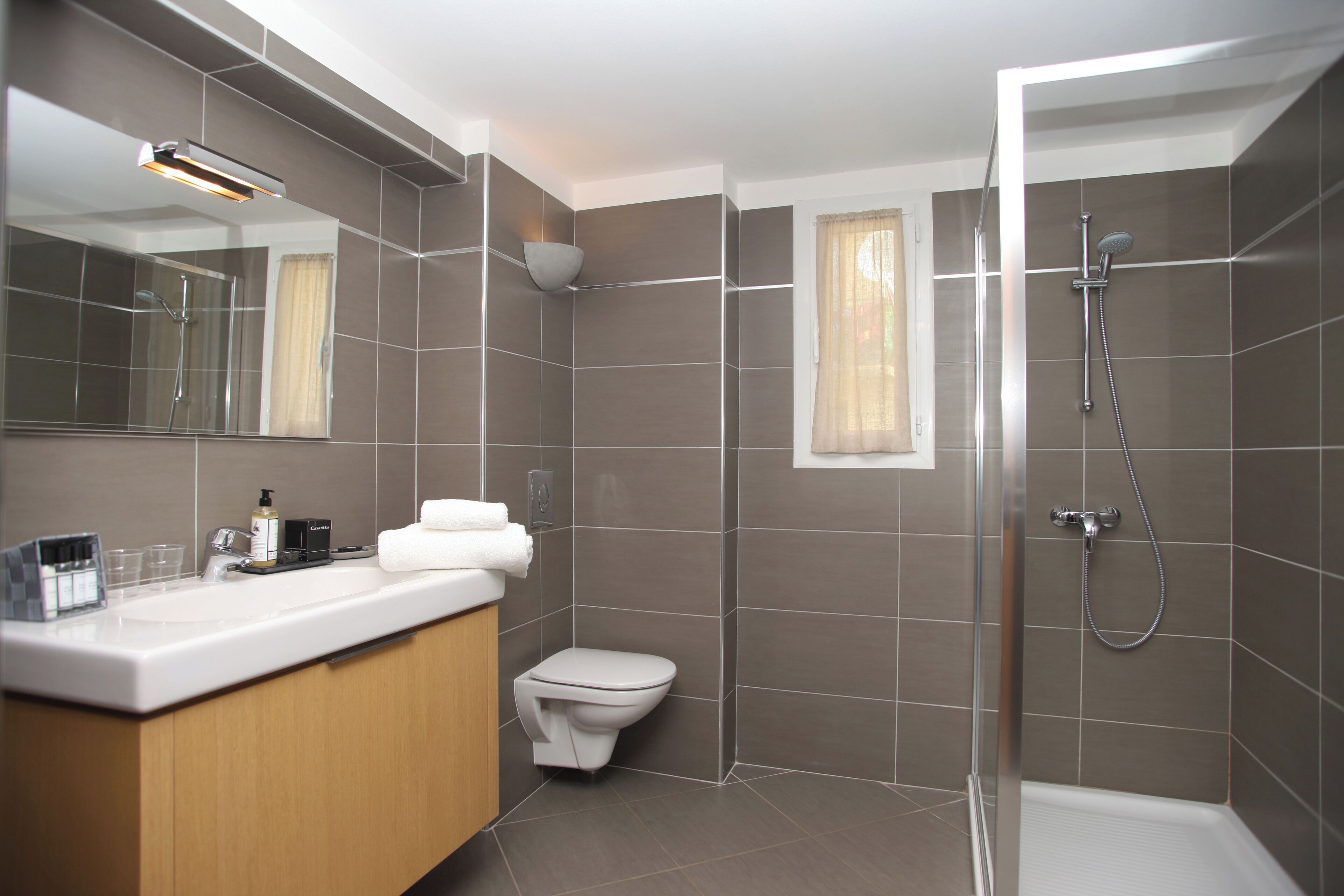 A modern bathroom with a shower, toilet, and vanity.