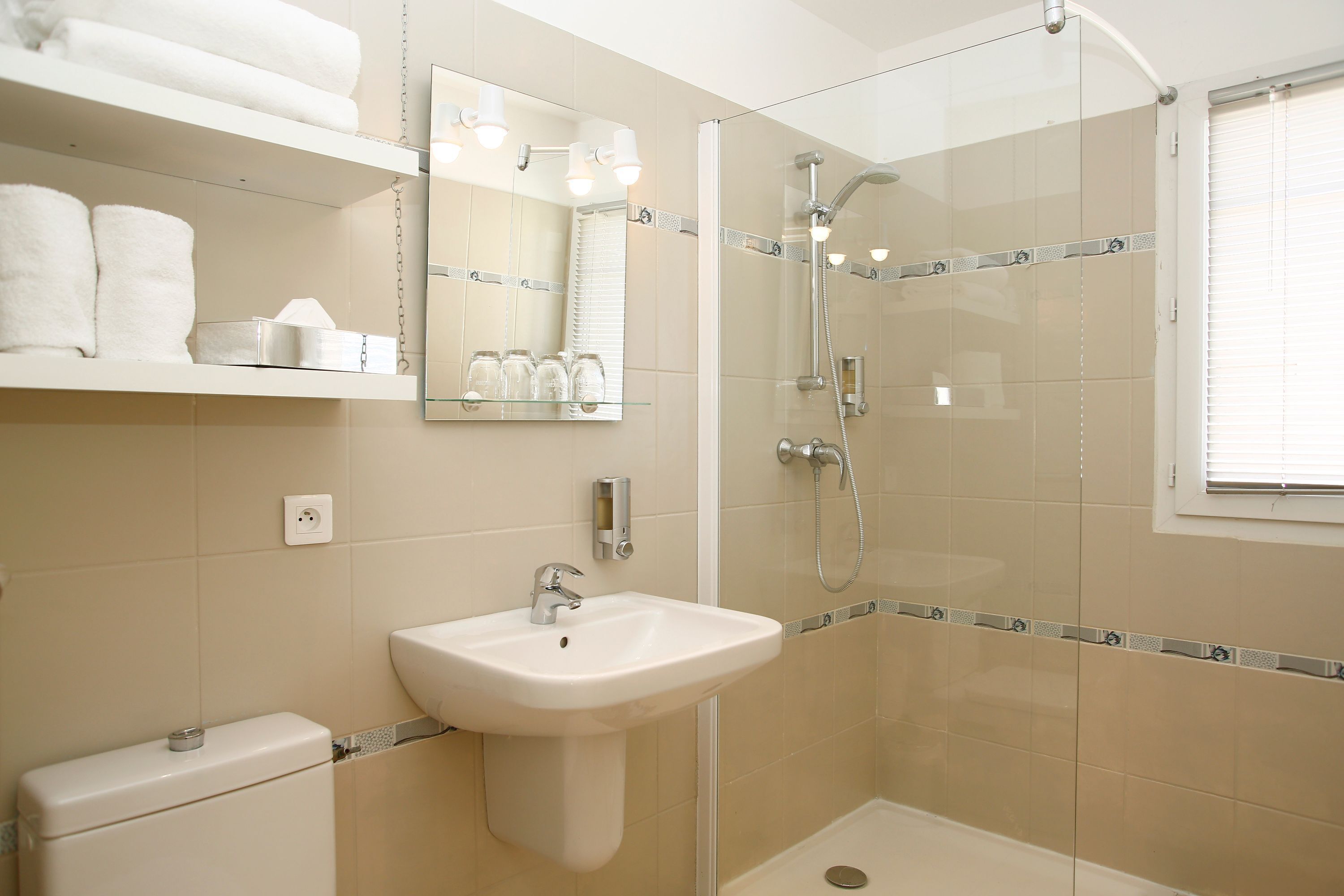 A modern bathroom with a glass-enclosed shower, a white sink, and a mirror above the sink.