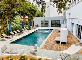 Una piscina con sillones de descanso y una terraza de madera.