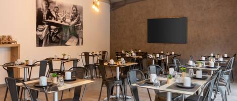 A dining area with multiple tables and chairs, a blackboard on the wall, and a hanging light fixture.