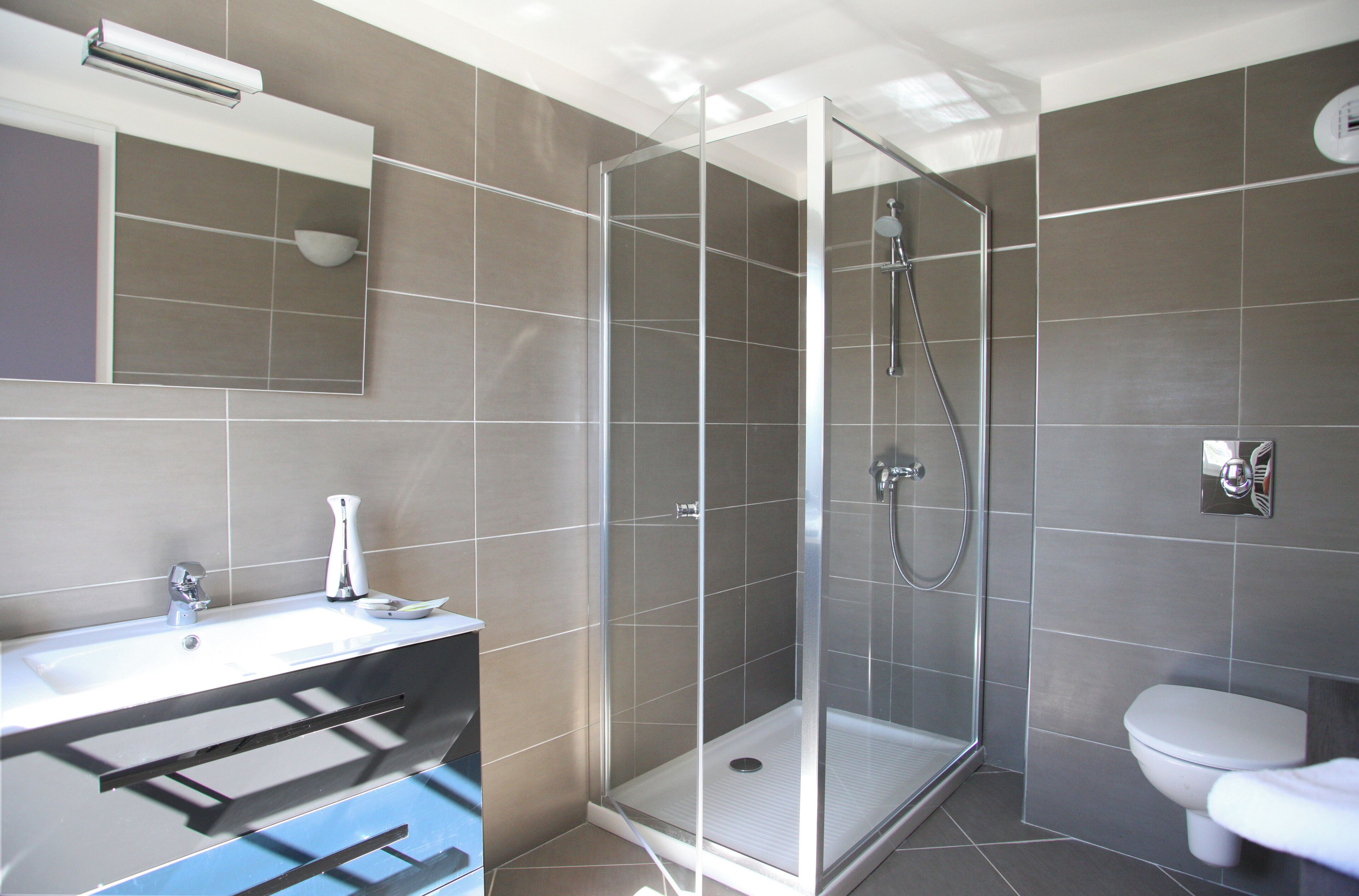 A modern bathroom with a glass-enclosed shower, a white sink, and a toilet.