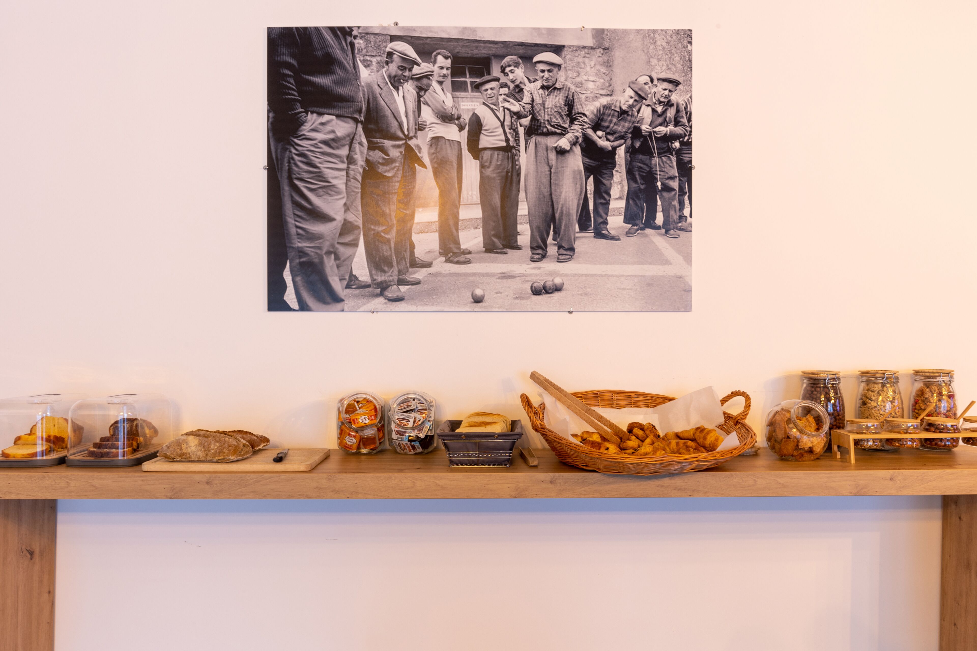 A vintage photograph of men playing cricket, a wooden shelf with bread, pastries, and jars of preserves.