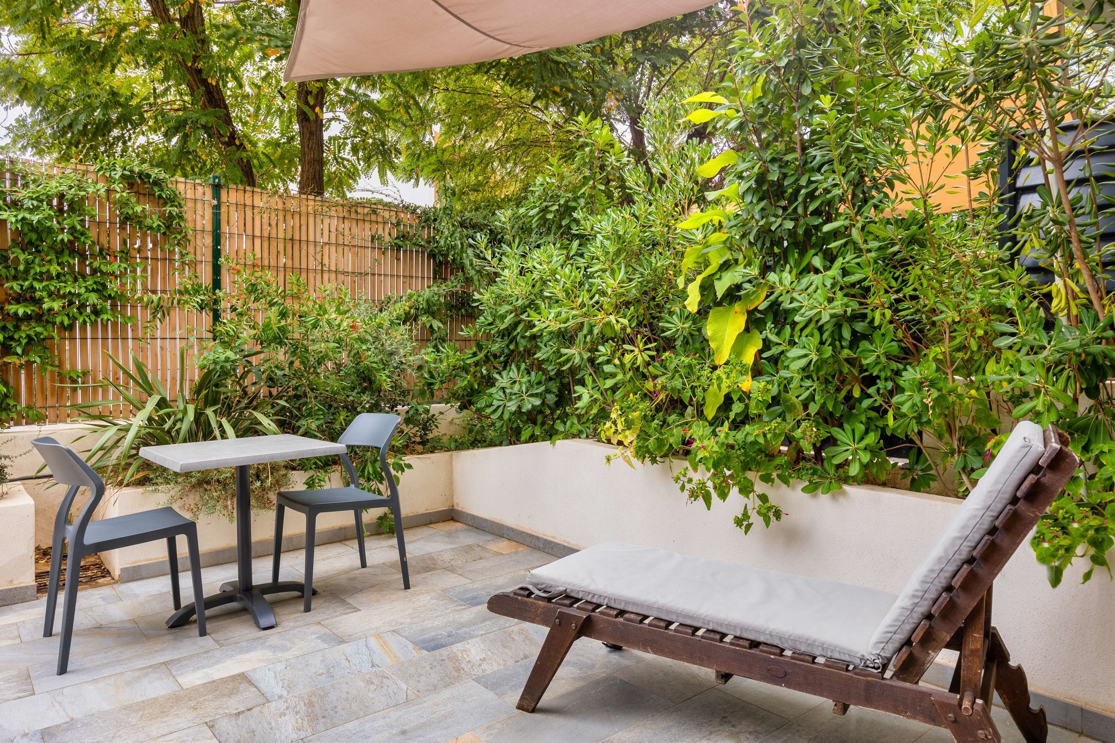 Un patio con una silla de descanso de madera, dos sillas y una mesa.